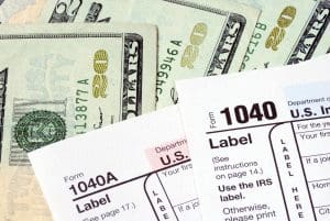 Money and 1040 forms symbolizing the new federal income tax returns
